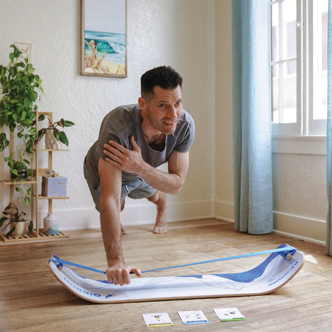Man doing a plank using the line on his Mountain design SlackBoard, with exercise cards on the ground