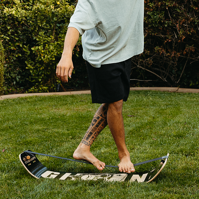 Person walking on a caesar slackboard in a grassy area.