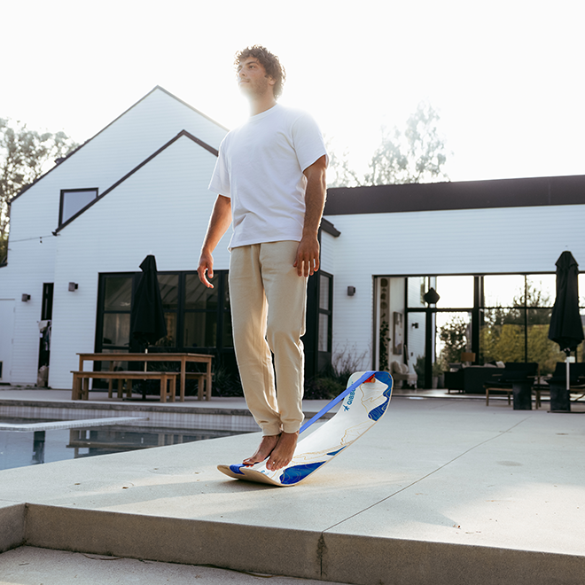 Person balancing on a Mountain SlackBoard in front of a modern house.