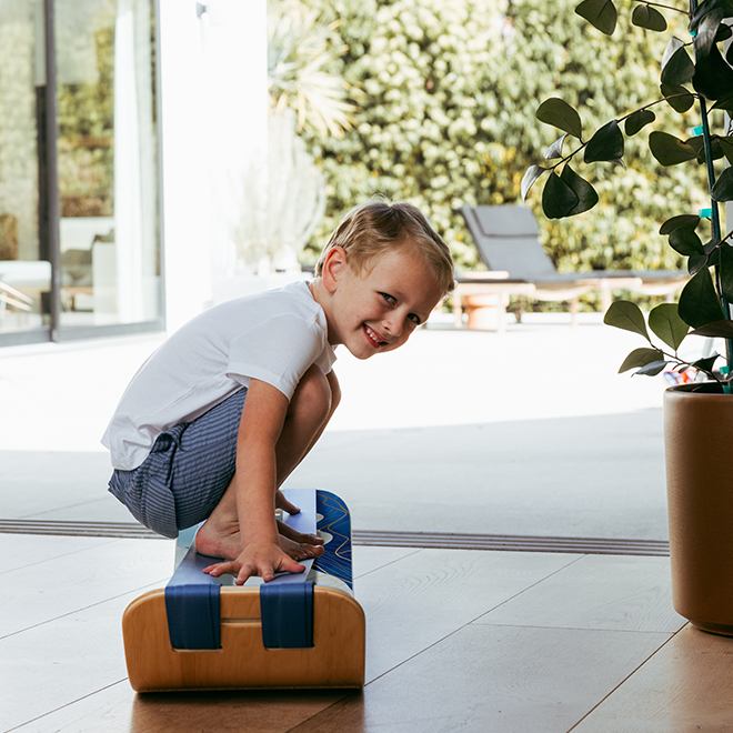 Child balancing on a mountain slackboard plus with plants in the background